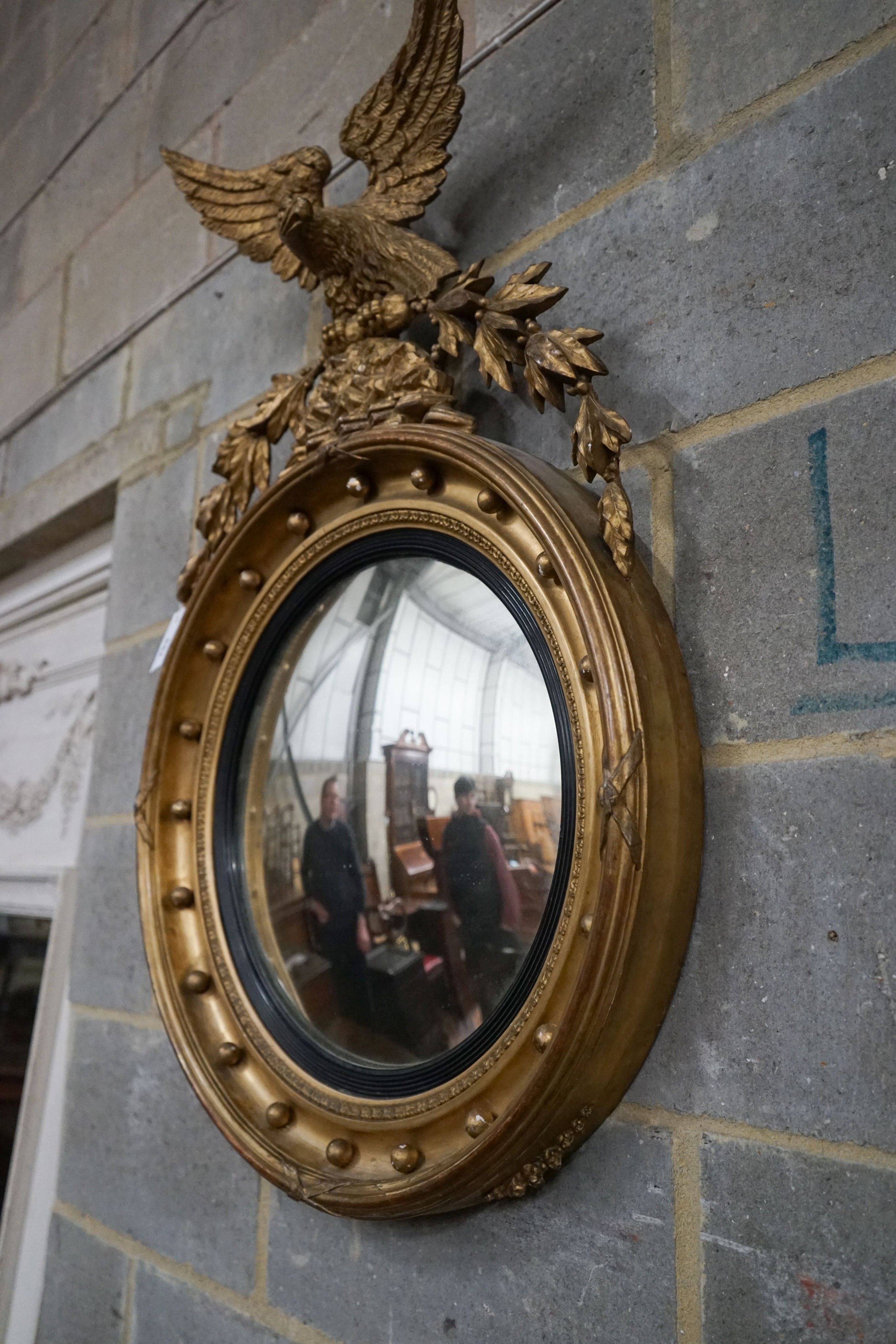 A Regency giltwood and gesso convex wall mirror with eagle pediment, width 60cm, height 94cm